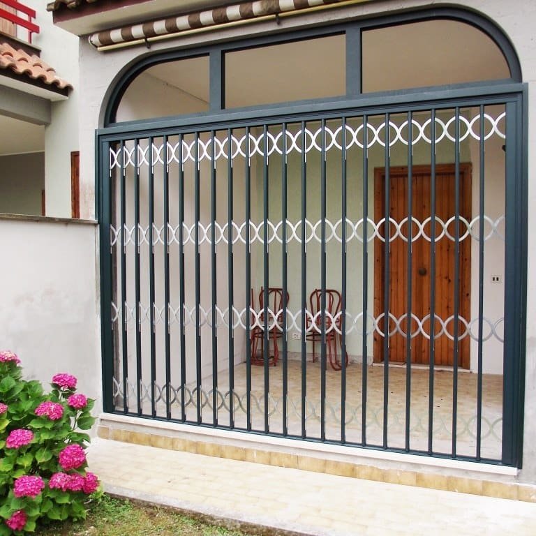 Grata di sicurezza ad arco in ferro verde con decori, su un ingresso